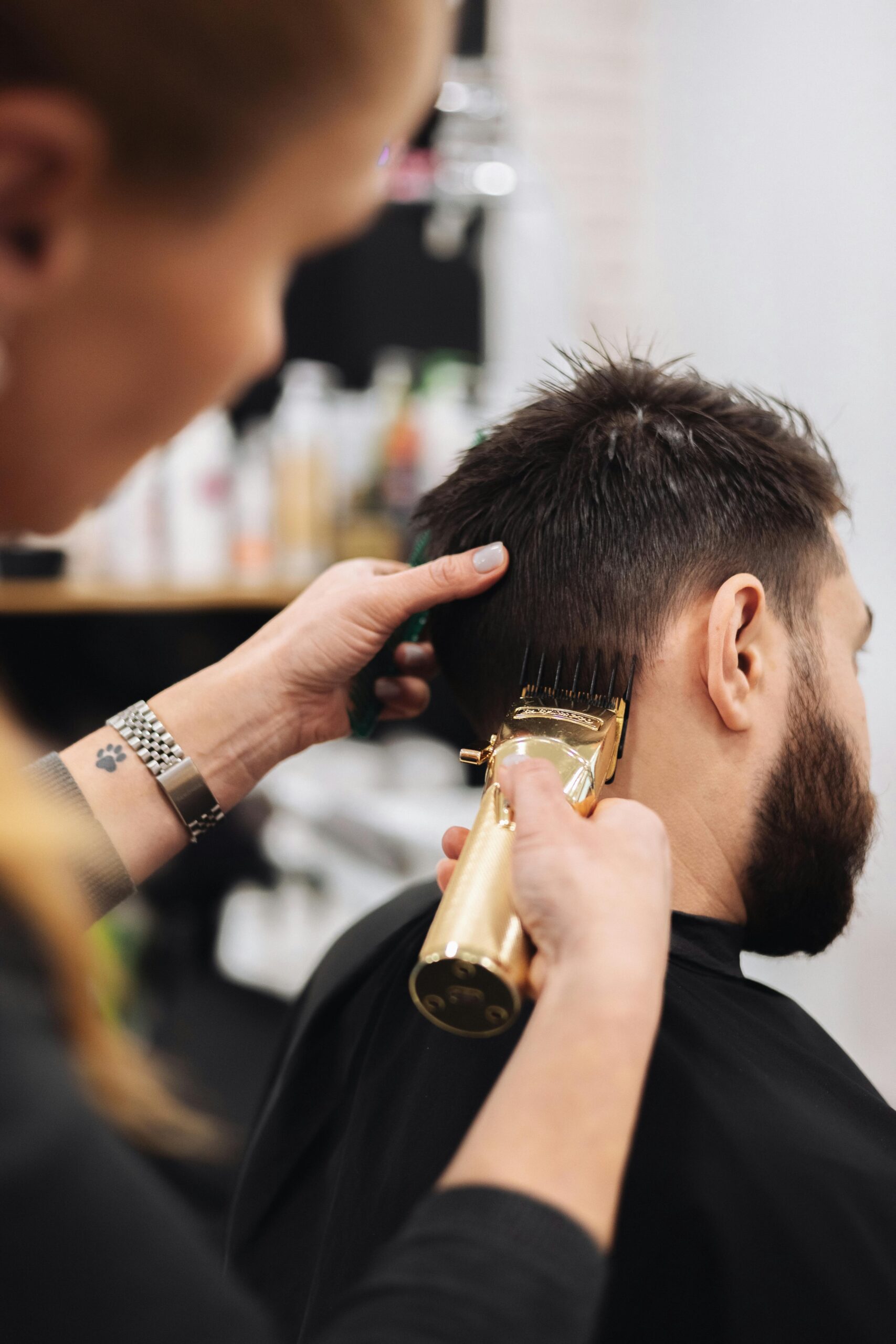 Close-up of a barber trimming a man's hair with clippers in a salon.